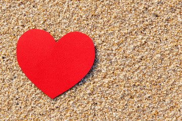 Red paper heart at beach sand. Romantic background, anniversary card template.