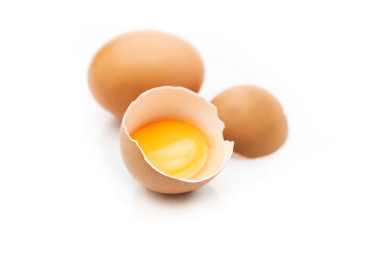 Huevo moreno roto con fondo blanco y yema dentro