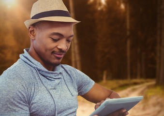 man on tablet in forest trees