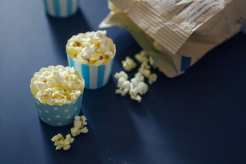 Three cupcake cases filled with salty caramel popcorn on chalkboard background. Fun snack for a children party or a movie night.