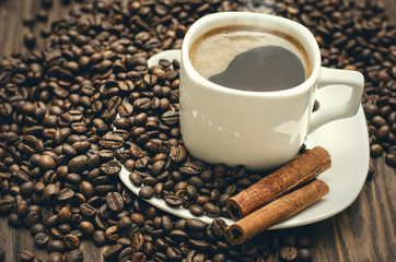 Coffee cup with beans and cinamon on a wooden table