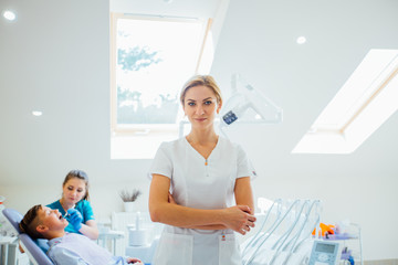 Fototapeta na wymiar young female dentist with tools over medical office background
