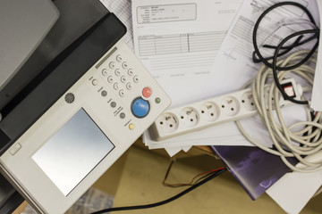 The printer next to the table with a mess.