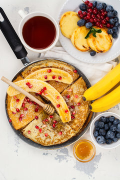 Sweet crepes with banana, honey and pomegranate seeds