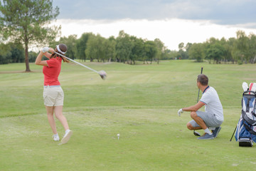 Woman playing golf, husband watching shot