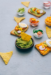 Top view of Freshly Homemade Guacamole with toast on rustic grey texture.