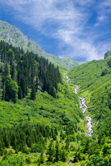 Fototapeta na wymiar Waterfall in the green valley between the mountains in summer, Gorgit Highland.