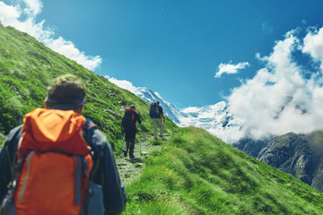 Fototapeta na wymiar hikers with backpacks on the trail in the Apls, Swiss mountains. Trek near Matterhorn mount, mountain ridge on background