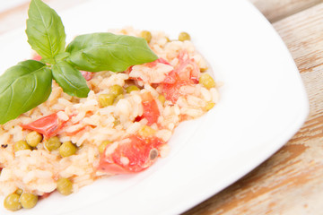 Risotto with tomato and pea on a wooden background 