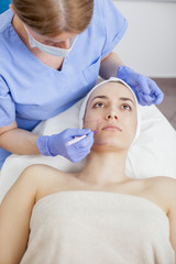 Naklejka premium Young beautiful woman in the beauty salon on the face treatment