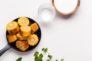 Grilled corn cons with sour cream sauce and cilantro on white background with copy space. Vegetarian bbq concept