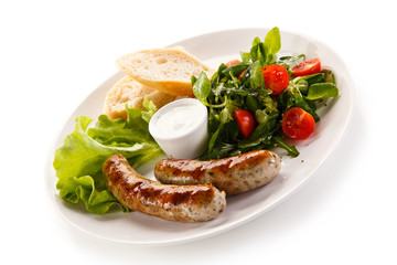 Grilled sausages with vegetables on white background