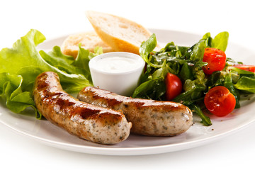 Grilled sausages with vegetables on white background