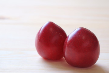 Closed up of Two Heart Shaped Ripe Gulf Ruby Plum Fruits on Wooden Table 