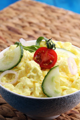 A delicious homemade creamy potato salad on a picnic table.