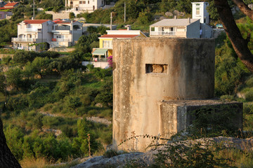 Fototapeta na wymiar ein Bunker aus dem Balkankrieg steht vor Ferienhäusern an der kroatischen Adriaküste