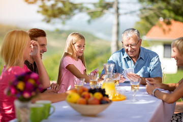 family sitting at table playing cards.