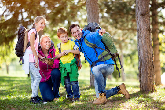 smiling family on hiking shows with finger destination.