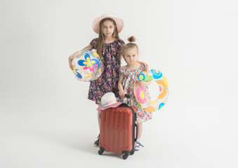 Sad sisters are standing near a suitcase
