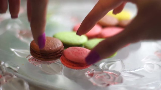 close up of girl puts on the plate color macaroon cookies