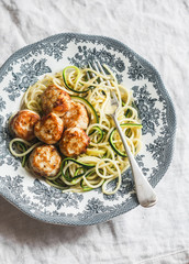 Spaghetti with cheesy chicken meatballs and zucchini noodles. Delicious lunch on a light background, top view