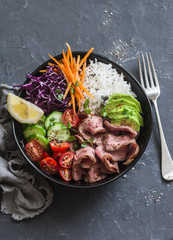 Beef steak, rice and vegetable power bowl. Healthy balanced food concept. On a dark background, top view