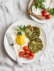Fried egg, zucchini fritters and cream cheese sandwich - delicious breakfast, brunch or snack. On a light background, top view