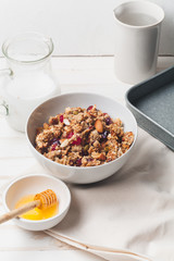Morning granola with dried fruits, honey, milk and berries on white wooden background. Top view with copy space