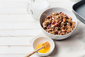 Morning granola with dried fruits, honey, milk and berries on white wooden background. Top view with copy space