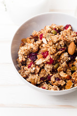 Morning granola with dried fruits, honey, milk and berries on white wooden background. Side view, close up