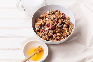 Morning granola with dried fruits, honey, milk and berries on white wooden background. Top view with copy space