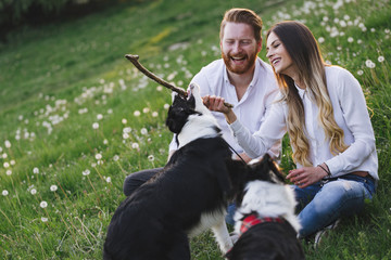 Beautiful couple cuddling and walking dogs outdoors