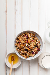 Morning granola with dried fruits, honey, milk and berries on white wooden background. Top view with copy space