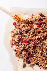 Baked granola with cranberry and honey on parchment sheet on white background. Morning concept.