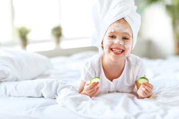happy child girl in towel with mask on face