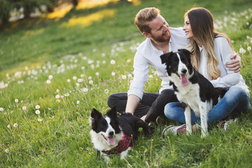 Naklejka na ściany i meble Romantic couple in love walking dogs in nature and smiling