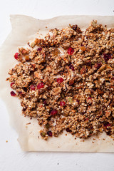 Baked granola with cranberry and honey on parchment sheet on white background. Morning concept