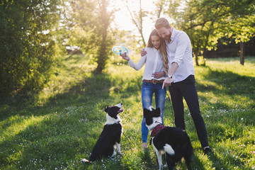 Romantic couple in love walking dogs in nature and smiling