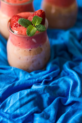 Fresh strawberry and banana smoothies decorated berry and mint leaves on blue napkin. Selective focus