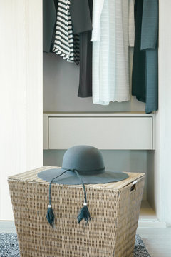Black hat on basket with cloths hanging in closet in background