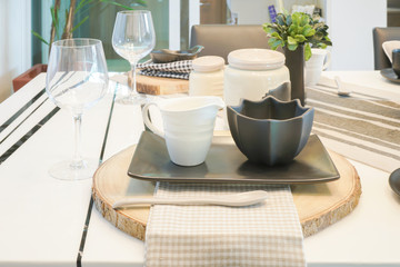 Black and white pottery cups setting on wooden cutting plate on dining table