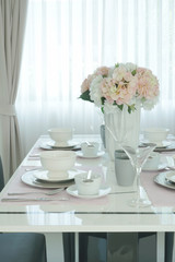 Fototapeta na wymiar Pink flower at the center of romantic dining table in dining room