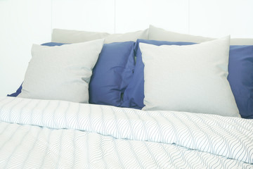 White and blue pillows on bed with stripped bedding at home