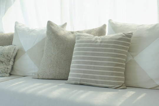 Stripe and beige pillows setting on sofa next to window