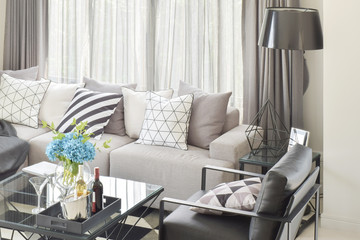 Mix pattern pillows in gray tone sofa and wine bottles on center table in living room