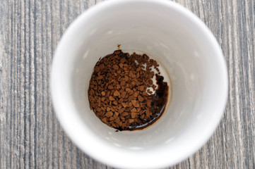 Mug of hot instant coffee on a wooden table with a spoon
