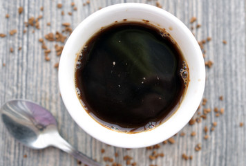 Mug of hot instant coffee on a wooden table with a spoon
