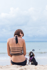 Young attractive girl with her pet dog Beagle at the beach of tropical island Bali, Indonesia. Happy moments.