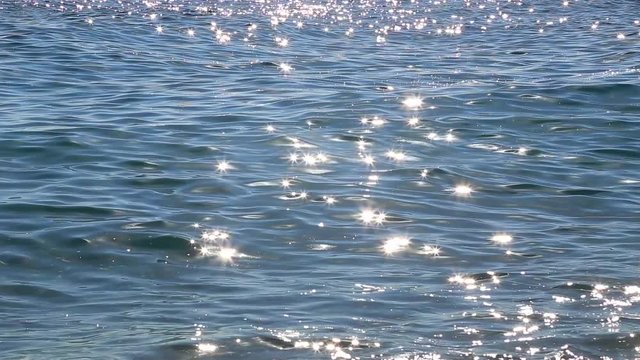 Beautiful blue sea water background with bright sunny sparkles on surface of waves. Real time full hd video footage.