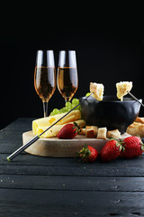 Gourmet Swiss fondue dinner with assorted cheeses on a board and